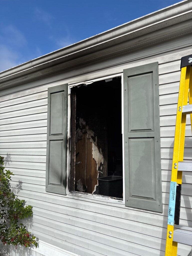 Burned out window with charred framing on a house exterior after a fire