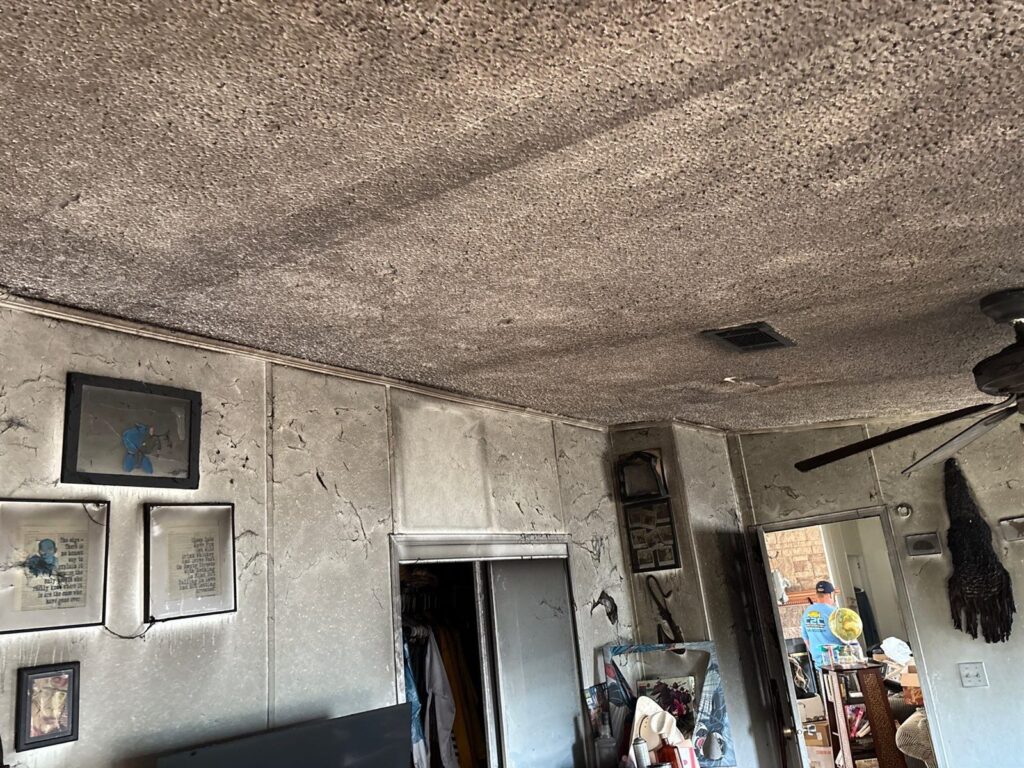 Fire damaged interior with heavy soot across the ceiling and walls before cleanup