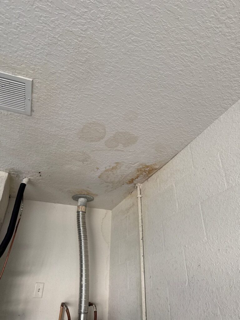 Water stained ceiling with visible discoloration around a flue pipe during a damage inspection