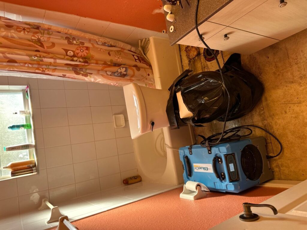 Commercial dehumidifier and drying equipment placed in a water damaged bathroom during structural drying